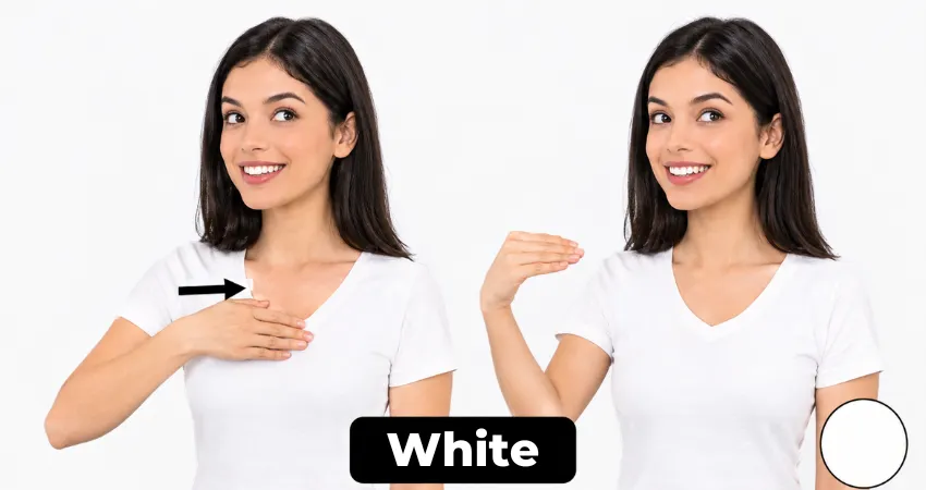 Smiling woman in a white shirt shows the ASL sign for white by pulling her hand from her chest, fingers closing.