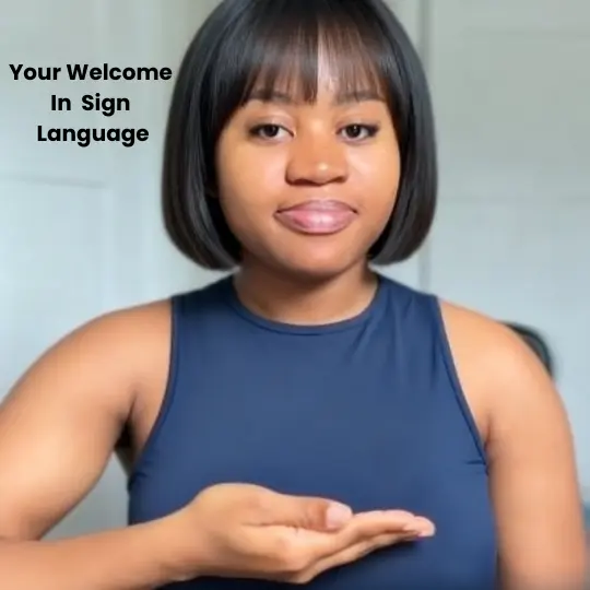 Woman signing YOU'RE WELCOME in ASL with flat hand moving forward from chin outward